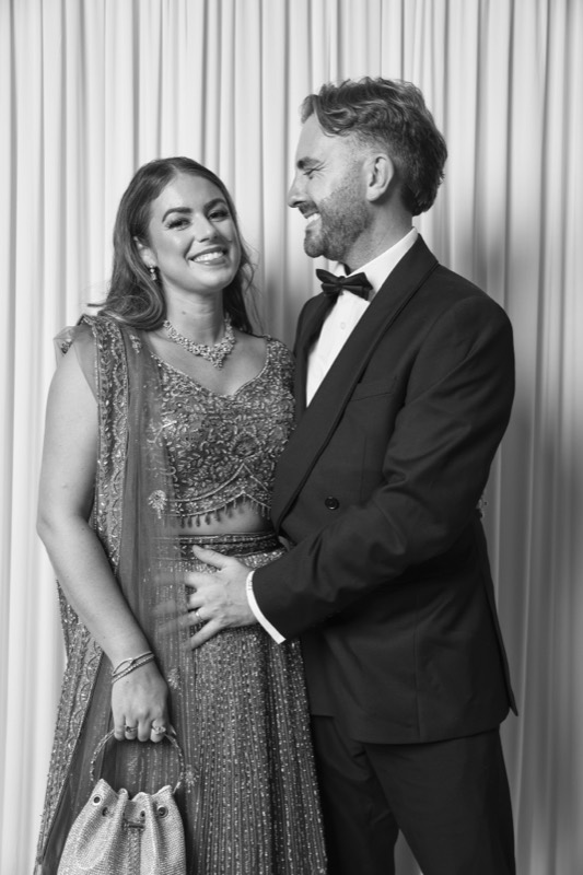 A couple in evening wear smile at each other