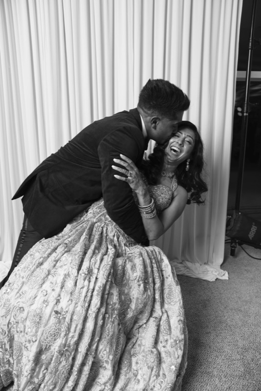 A groom dips his bride in her embroidered lehenga as she laughs