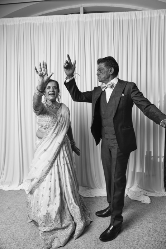 An older couple dance with their arms in the air